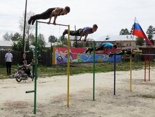 Заниматься на старых турниках было уже небезопасно, и юные жители поселка использовали для тренировок остановочные павильоны и ограждения. Отстроить удобную и безопасную площадку любителям воркаута помогли местные власти Заниматься на старых турниках было уже небезопасно, и юные жители поселка использовали для тренировок остановочные павильоны и ограждения. Отстроить удобную и безопасную площадку любителям воркаута помогли местные власти, дорожники, энергетики, предприниматели, производители сгущенного молока, инициативные жители. Молодые спортсмены и сами активно потрудились на строительстве площадки, кроме того, рядом с ними две недели работали подростки из трудового отряда.  Уличные тренировки, или воркаут привлекают молодежь своей экономичностью - на занятия не нужно тратить деньги, нет необходимости в сложном специализированном инвентаре. В целом этим спортивным направлением занимаются два десятка тяжинцев возрастом от 13 до 18 лет. Они крутят «солнышко», выполняют сложнейшие упражнения «Выход ангела» и «Самолет», а теперь будут осваивать новые турники и брусья.  Атлетичные и подтянутые ребята, ведущие здоровый образ жизни, стали примером для многих поселковых подростков. Спортсмены уже проводят небольшие соревнования и показательные выступления.  На будущий год обустройство площадки для воркаута продолжится, здесь установят тренажер-рукоход и гимнастические кольца.